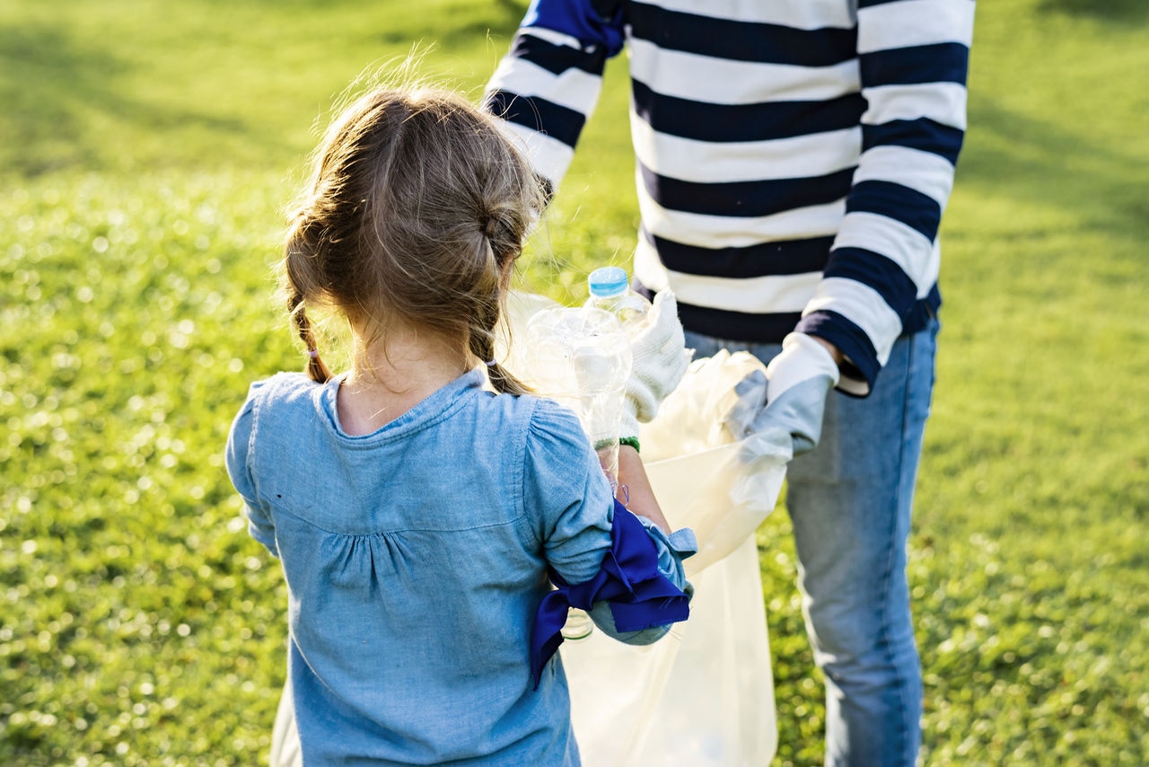 Young girl and mother working together to clean-up trash in the park.